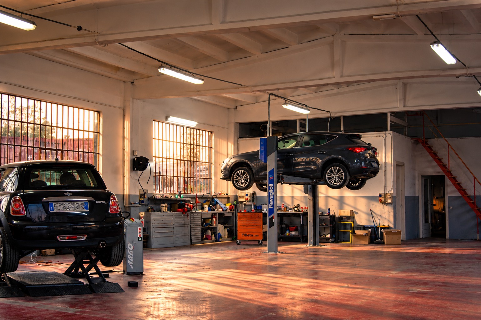 L'interno dell'officina con due ponti: una Mini su un ponte a forbice e una Seat su un ponte a due colonne