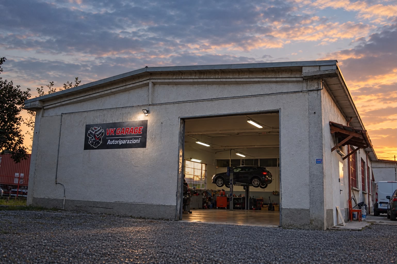 VK Garage al tramonto, con l'insegna sulla facciata e il portone aperto sull'officina